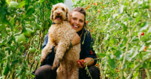 Angelika med sin hund Valle i växthuset på Angelikas gård på Österlen